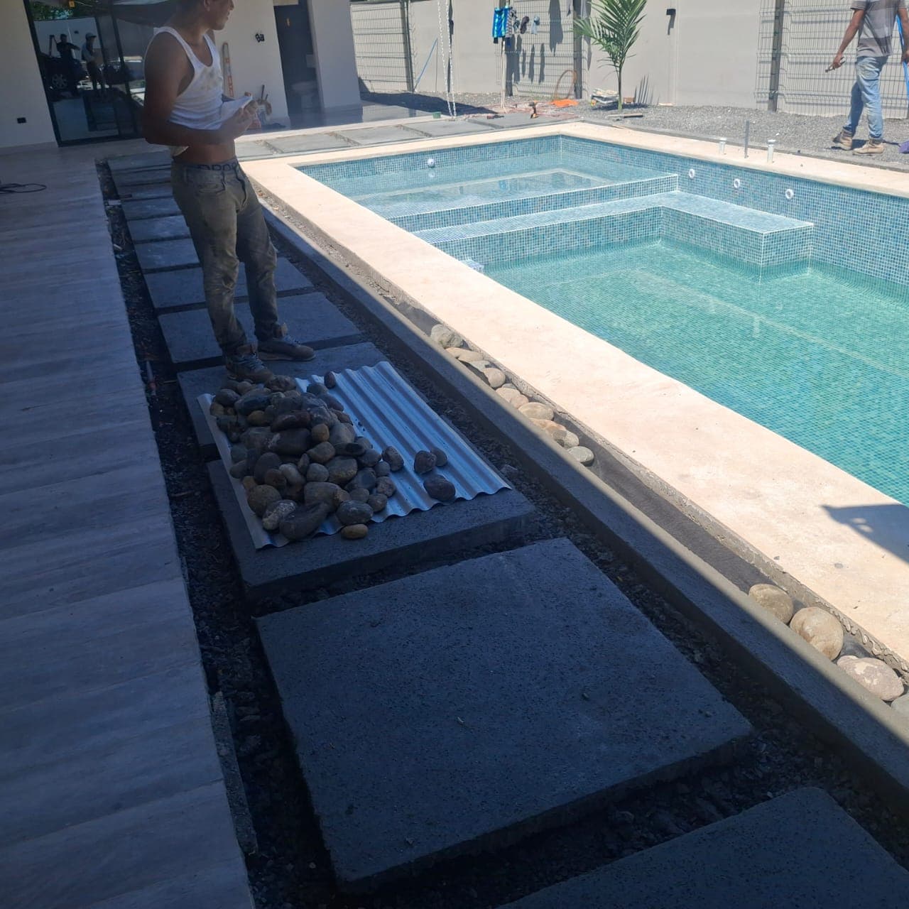 Square residential pool with deep blue liner and river rock border